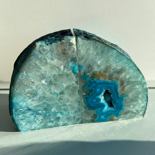 Blå agat geode sæt som dekorativ bogstøtte med glitrende krystaller indeni.